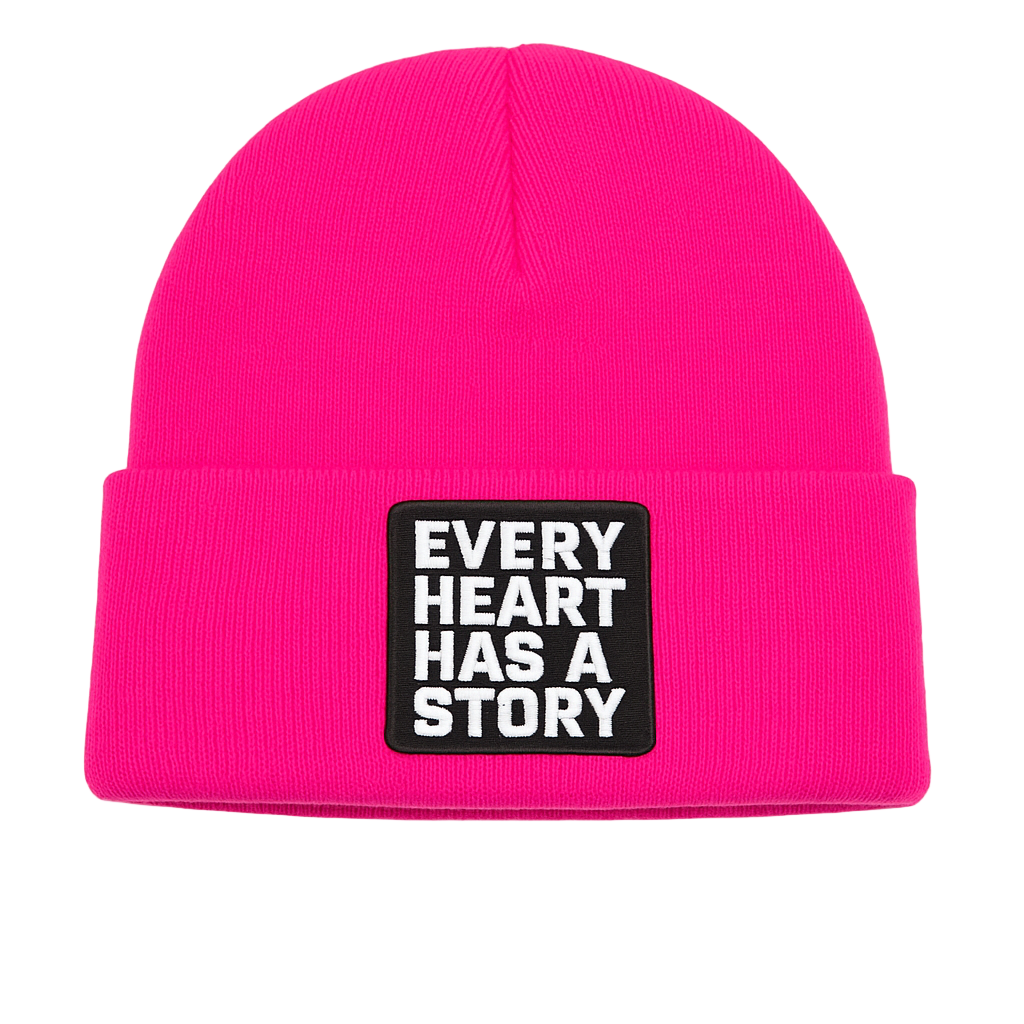 Pink beanie with a black patch that says 'Every Heart Has a Story' on a white background